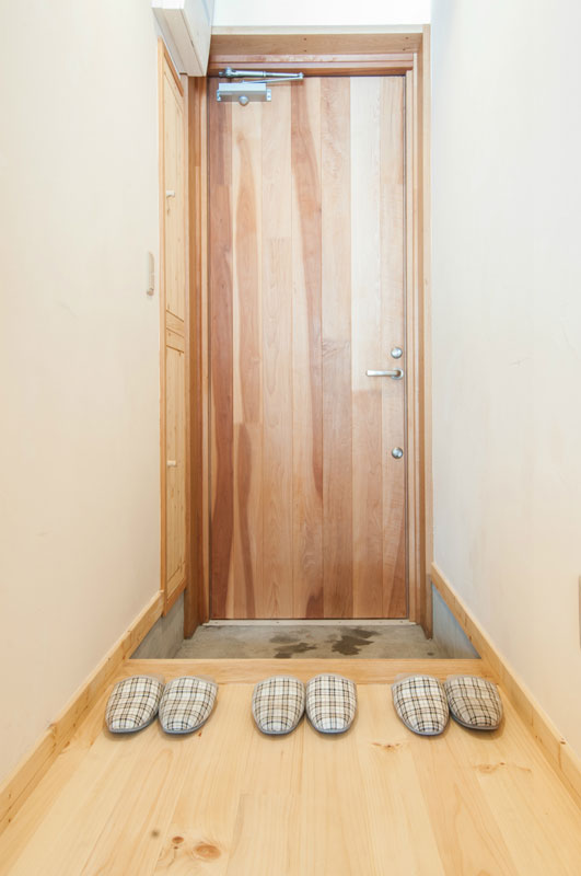玄関ドアは日本の木、サクラを使いました。向かって左側には多段の高さを変えられる靴入れあります。